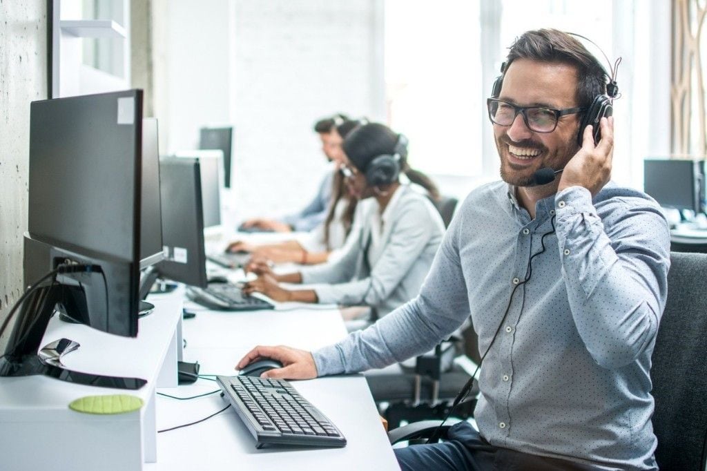 A smiling remote teammate wearing a headset at her workstation, ready to start the workday — the kind of dedicated, vetted teammate Online VA Team places with growing US businesses