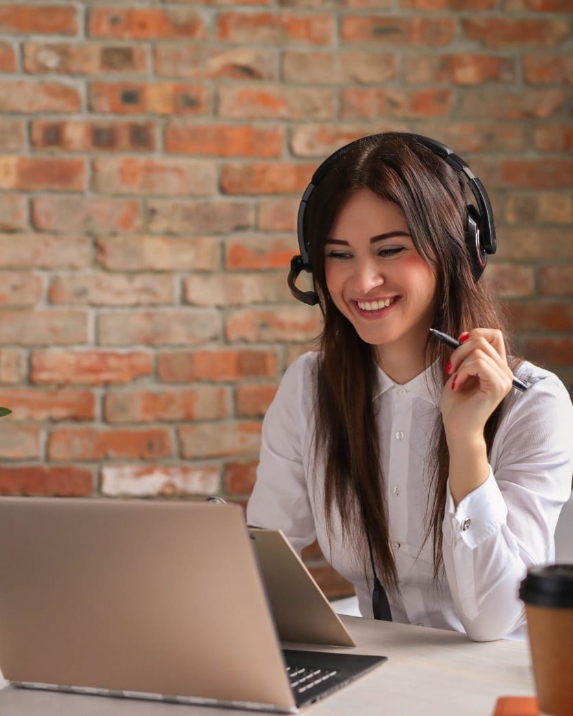 A confident teammate wearing a black headset, smiling at the camera in a sunlit home office — the kind of dedicated remote teammate Online VA Team places with growing US businesses