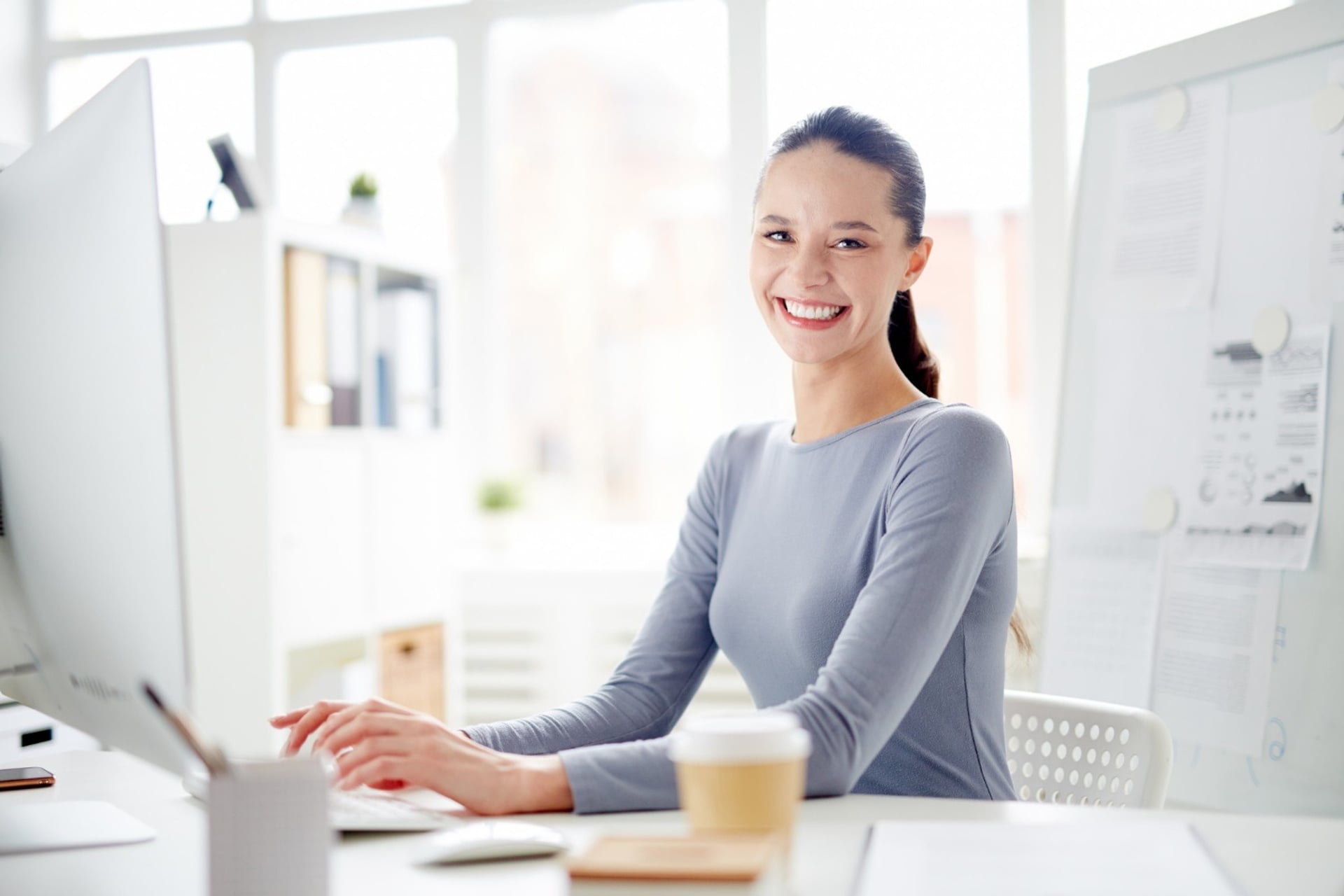 A smiling sales assistant working on a laptop, mid-call