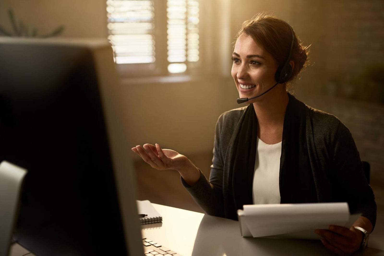 A newly placed virtual assistant at her workstation, headset on, smiling — the moment ownership of the work transfers from us to her