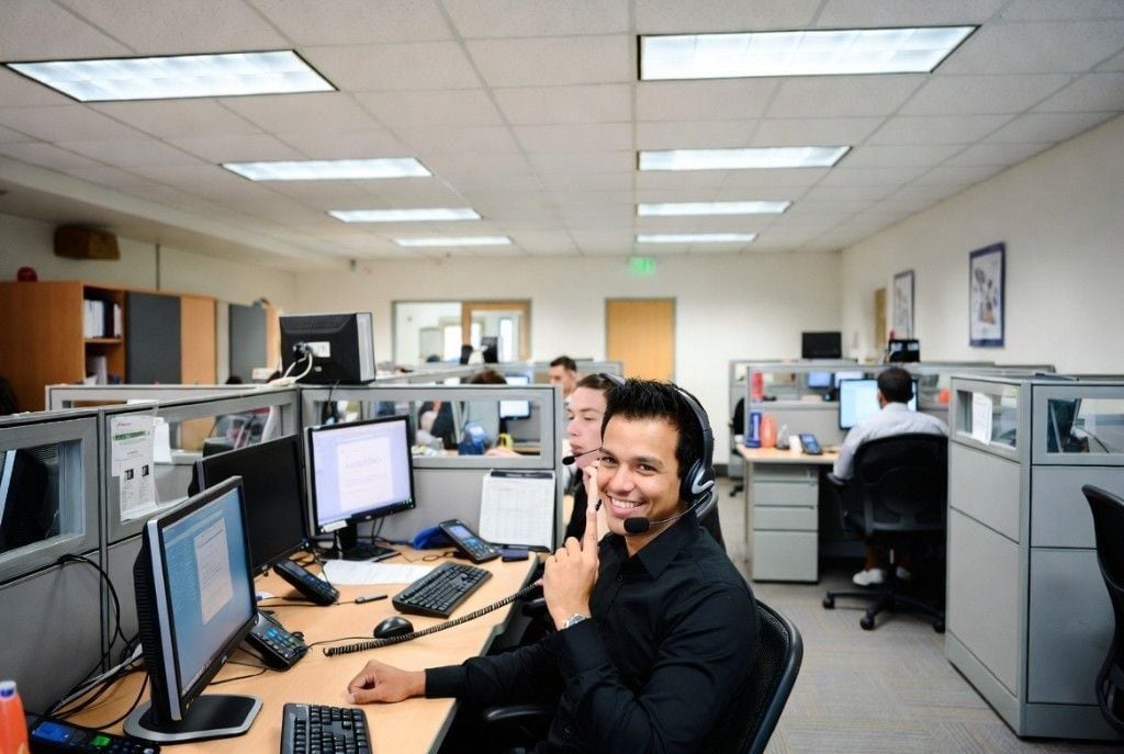 An Online VA Team bookkeeper focused on his multi-monitor cubicle — back-office reconciliation energy