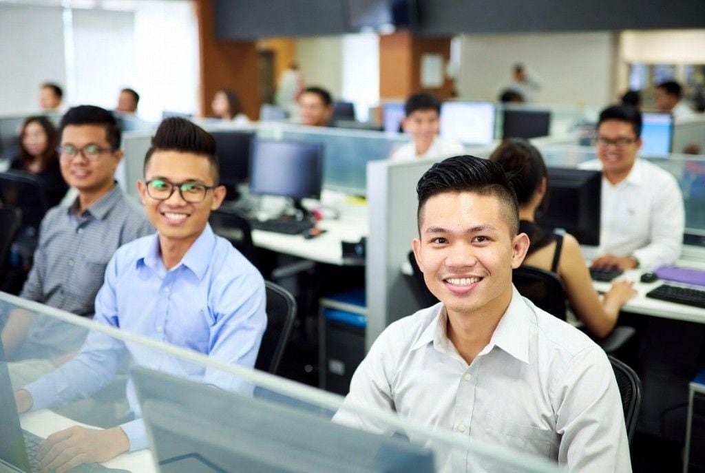 Two Online VA Team sales teammates in business attire working in a busy bullpen — outbound lead-gen energy