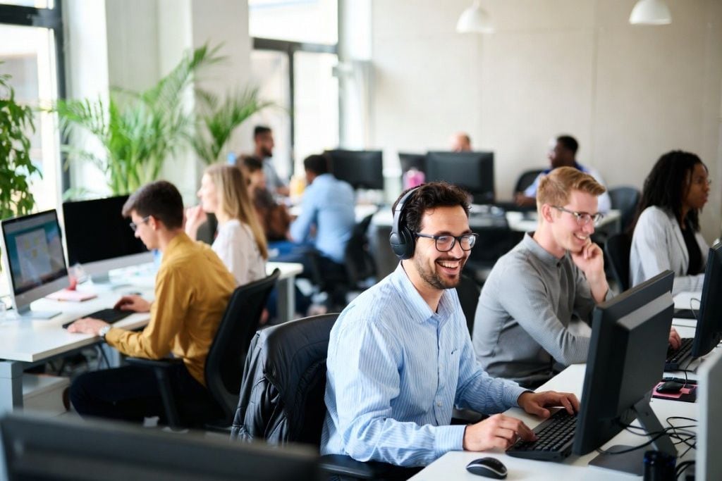 A smiling customer service representative wearing a headset, working from a clean home office