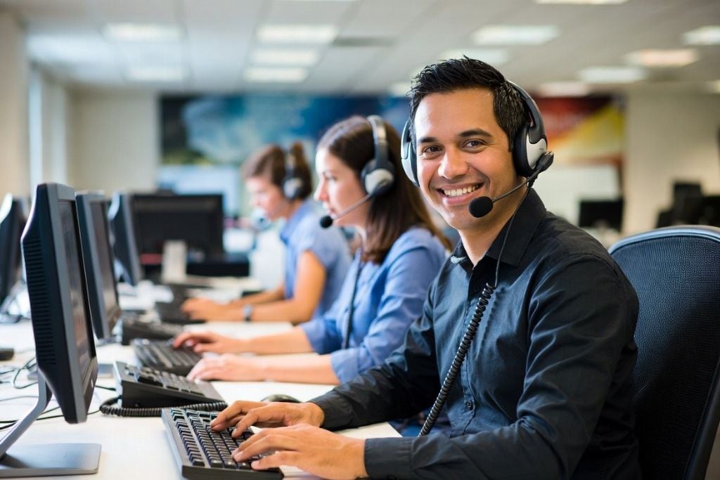 A live chat agent typing replies on a laptop, multiple conversations open in the chat window